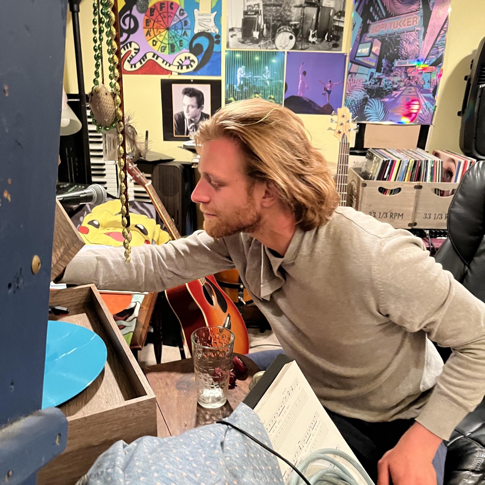 Kieran Specht in his home music studio, surrounded by guitars, vinyl records, and show posters