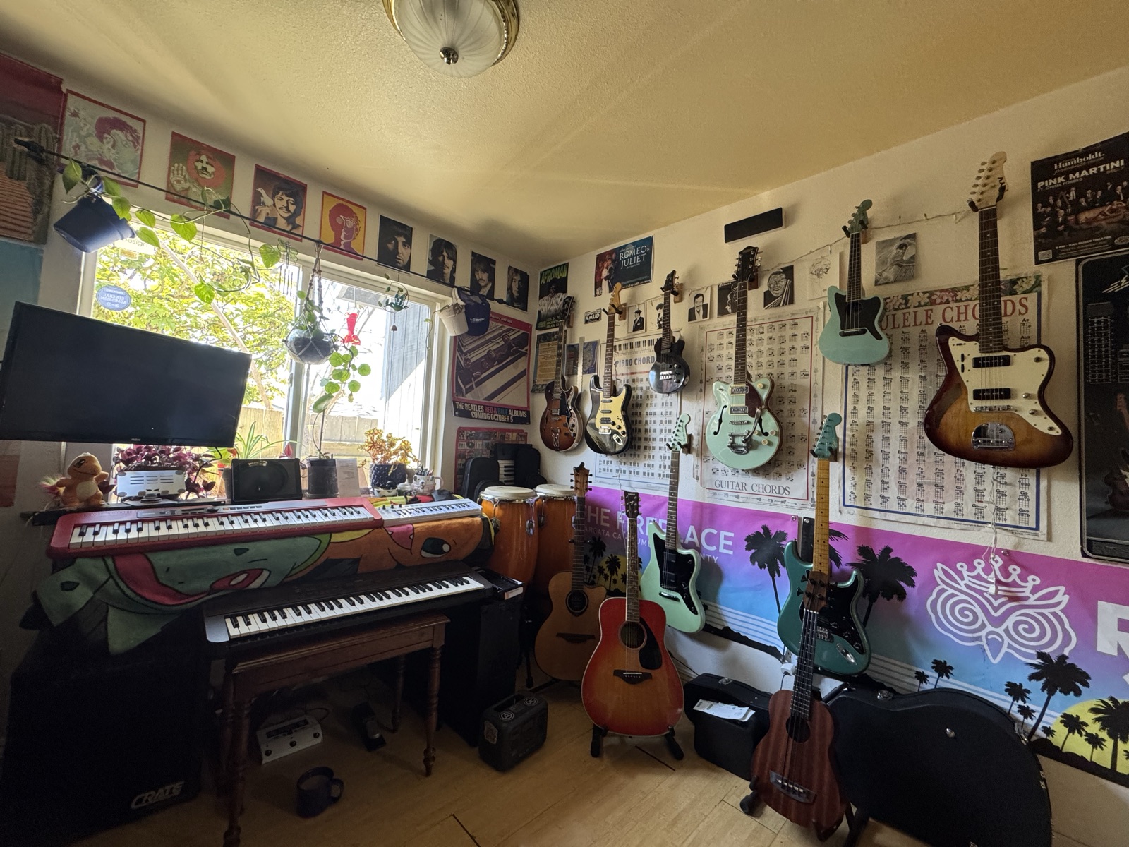 Kieran Specht's home music studio, walls lined with guitars, a piano, chord charts, and show posters