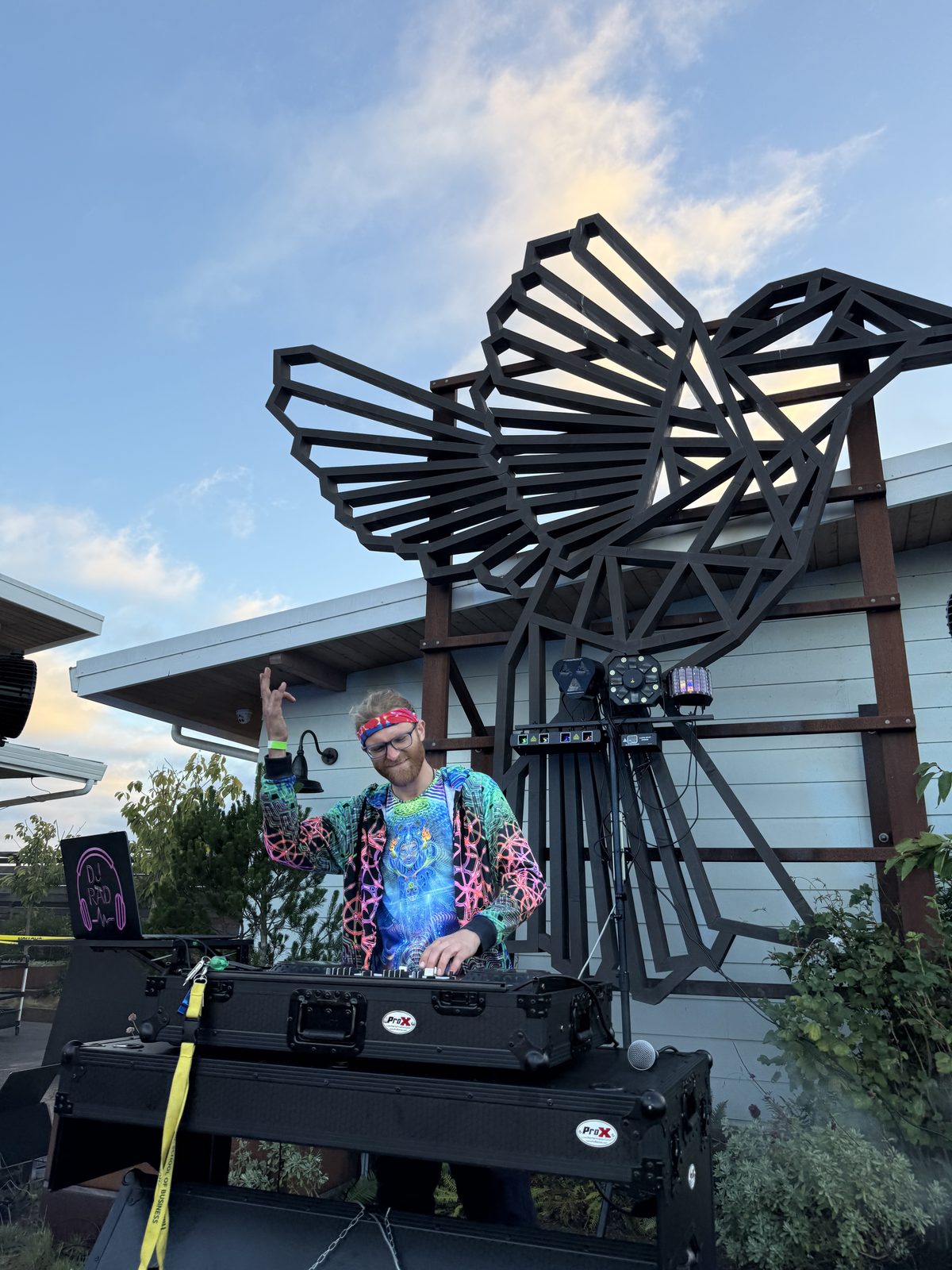 DJ R3$pecht performing at the Rooftop SOBE Rave, colorful outfit, hummingbird sculpture backdrop